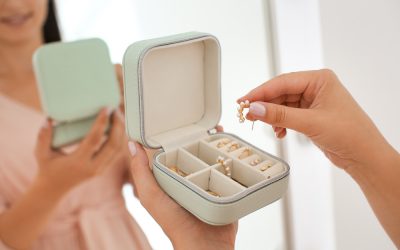 Young woman taking earring from jewelry box near mirror